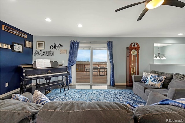 living room featuring ceiling fan with notable chandelier and hardwood / wood-style flooring