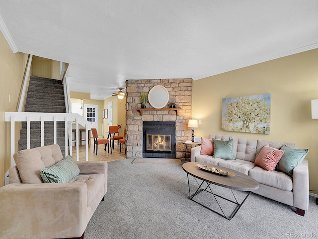 carpeted living room with ornamental molding, ceiling fan, and a fireplace