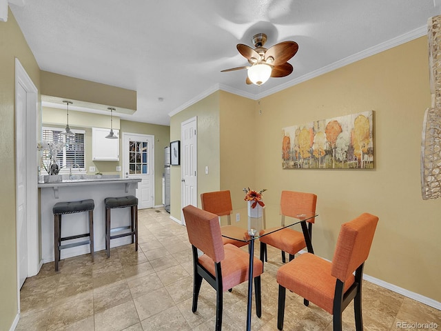 dining space with ornamental molding, sink, and ceiling fan