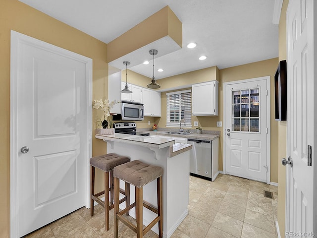 kitchen with sink, a breakfast bar area, white cabinetry, appliances with stainless steel finishes, and kitchen peninsula