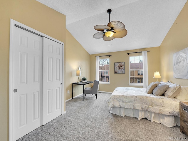 carpeted bedroom with ceiling fan, lofted ceiling, a closet, and a textured ceiling