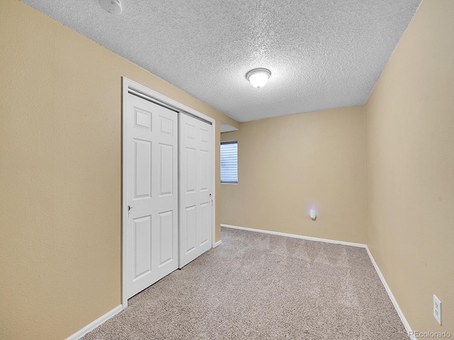 unfurnished bedroom featuring carpet floors, a textured ceiling, and a closet