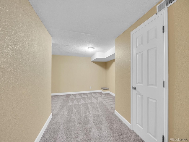 basement with light colored carpet and a textured ceiling