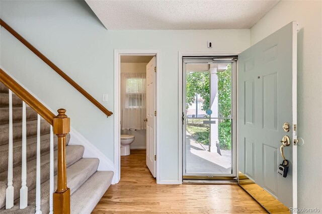 4081 Odessa St, Denver, CO 80249 - foyer entrance with light wood finished floors, stairway, a textured ceiling, and baseboards