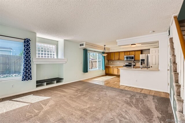 4081 Odessa St, Denver, CO 80249 - kitchen with stainless steel appliances, brown cabinets, light colored carpet, a peninsula, and baseboards