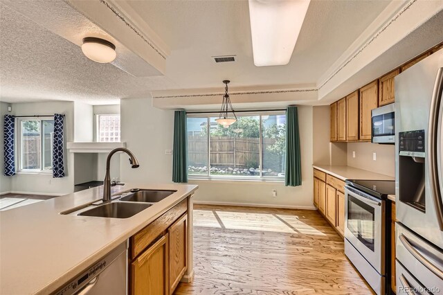 4081 Odessa St, Denver, CO 80249 - kitchen featuring appliances with stainless steel finishes, a sink, light wood-style floors, brown cabinetry, and light countertops