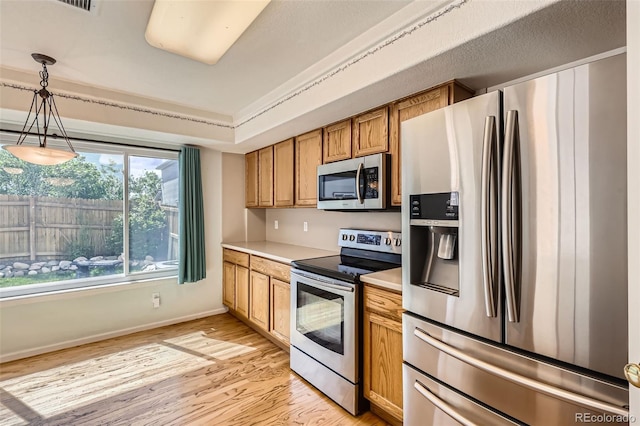 4081 Odessa St, Denver, CO 80249 - kitchen featuring stainless steel appliances, light wood-style floors, light countertops, pendant lighting, and baseboards