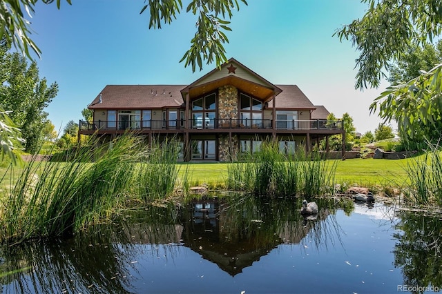 rear view of house with a water view and a lawn