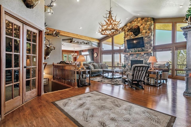 living room with a chandelier, wood-type flooring, and a stone fireplace