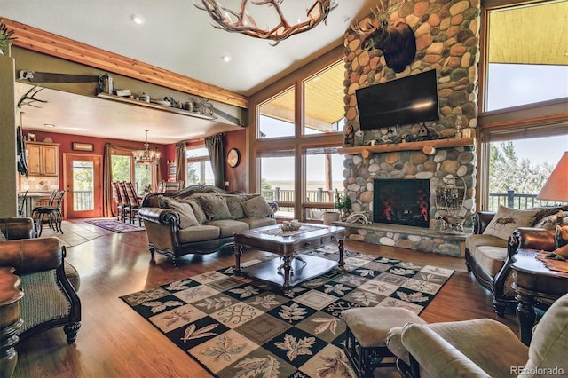 living room with high vaulted ceiling, a stone fireplace, beam ceiling, wood-type flooring, and a chandelier