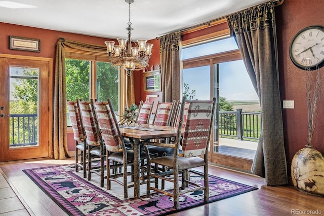 dining space with hardwood / wood-style floors and an inviting chandelier