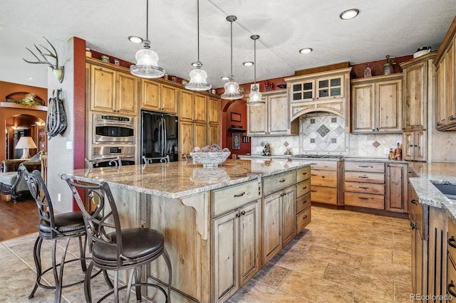 kitchen with light stone countertops, hanging light fixtures, a breakfast bar area, a kitchen island, and appliances with stainless steel finishes