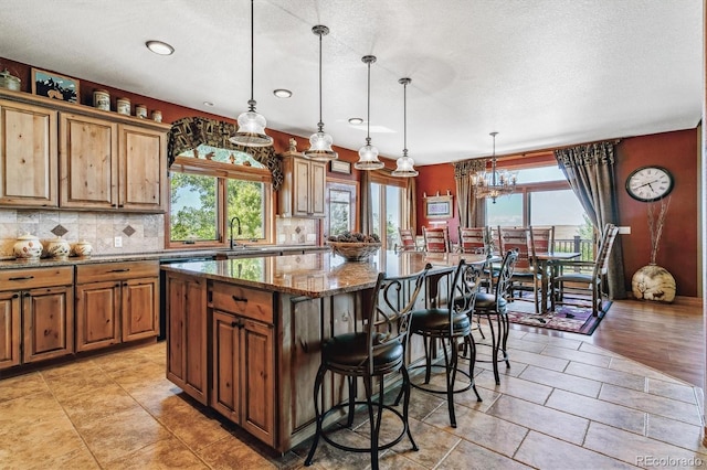 kitchen featuring stone counters, a center island, plenty of natural light, and hanging light fixtures