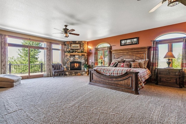 carpeted bedroom featuring a textured ceiling, ceiling fan, a fireplace, and access to outside