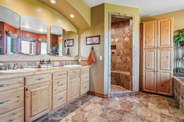 bathroom with a tile shower and vanity