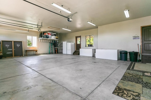 garage featuring white fridge, a garage door opener, and fridge