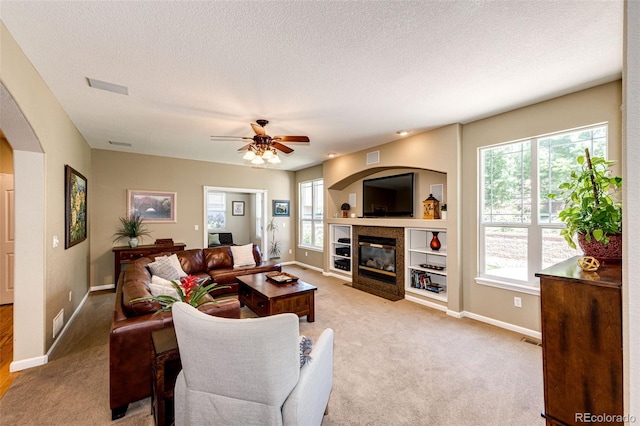 24036 E Kettle Pl, Aurora, CO 80016 - carpeted living area with healthy amount of natural light, a fireplace, a ceiling fan, arched walkways, and a textured ceiling