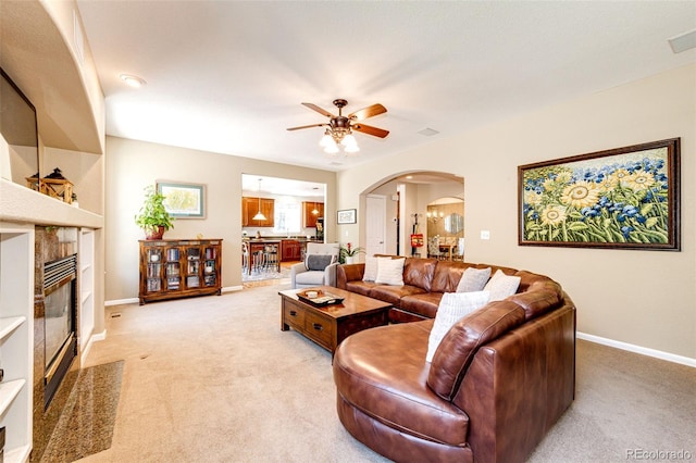 24036 E Kettle Pl, Aurora, CO 80016 - living room featuring arched walkways, light carpet, ceiling fan, and a tiled fireplace