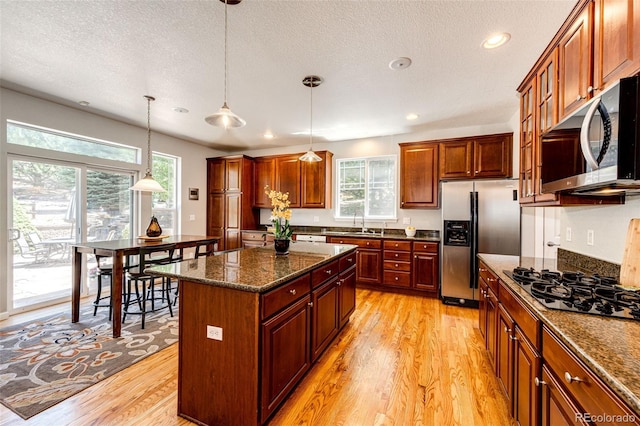 24036 E Kettle Pl, Aurora, CO 80016 - kitchen featuring stainless steel appliances, healthy amount of natural light, light wood-type flooring, a center island, and a textured ceiling