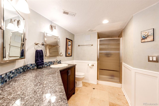 24036 E Kettle Pl, Aurora, CO 80016 - bathroom featuring a textured ceiling, vanity, a shower stall, wainscoting, and a decorative wall