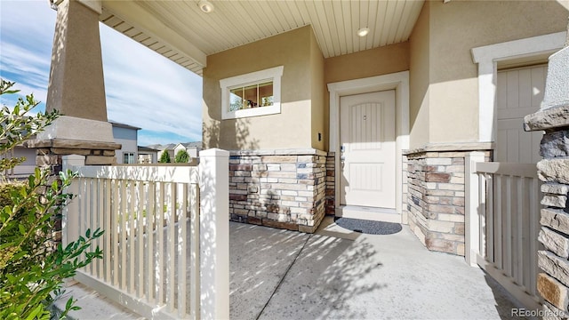 view of exterior entry with stone siding and stucco siding