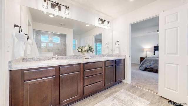 ensuite bathroom with double vanity, wood finished floors, ensuite bathroom, a sink, and a walk in shower