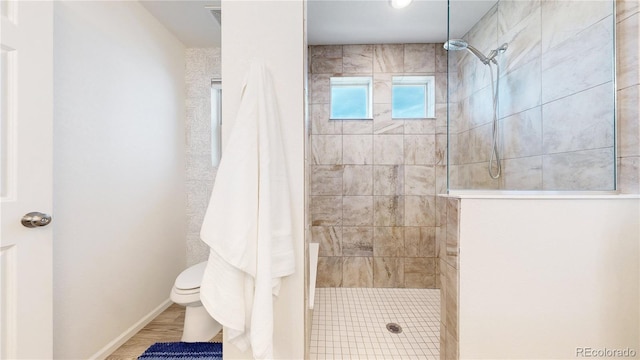 bathroom with a walk in shower, wood finished floors, toilet, and baseboards