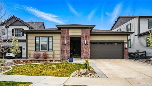 view of front facade featuring brick siding, an attached garage, a front lawn, and concrete driveway