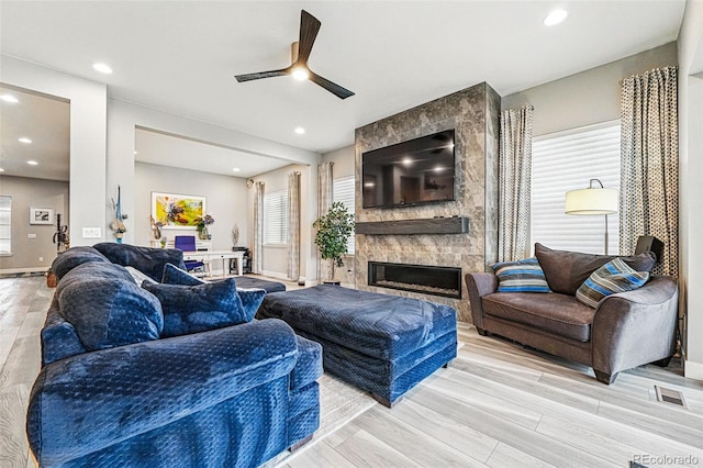 living area featuring a ceiling fan, visible vents, light wood finished floors, and plenty of natural light