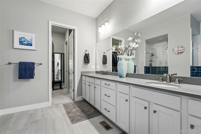 bathroom with double vanity, visible vents, a stall shower, and a sink