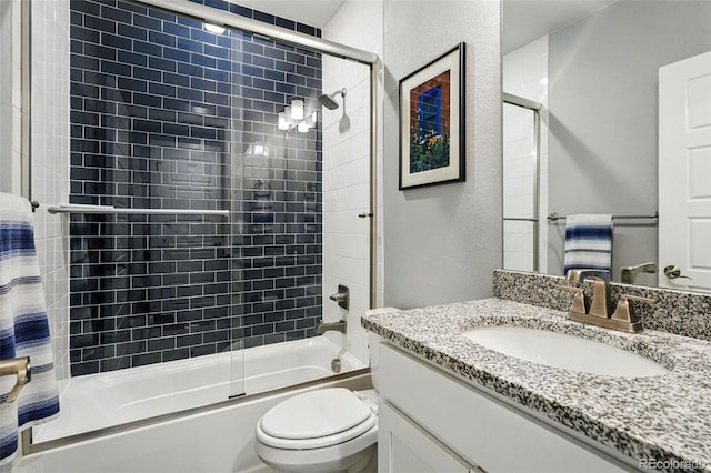 full bathroom featuring a textured wall, vanity, bath / shower combo with glass door, and toilet