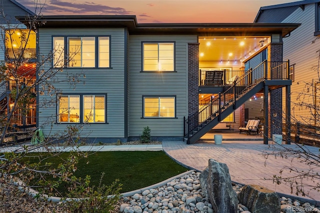 back of property with a patio area, a lawn, and stairs