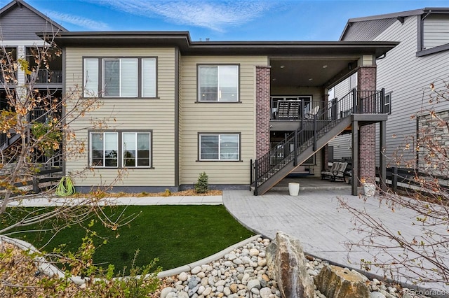 back of house featuring a yard, stairway, and a patio area
