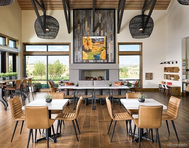 dining room featuring a towering ceiling, beamed ceiling, and a fireplace