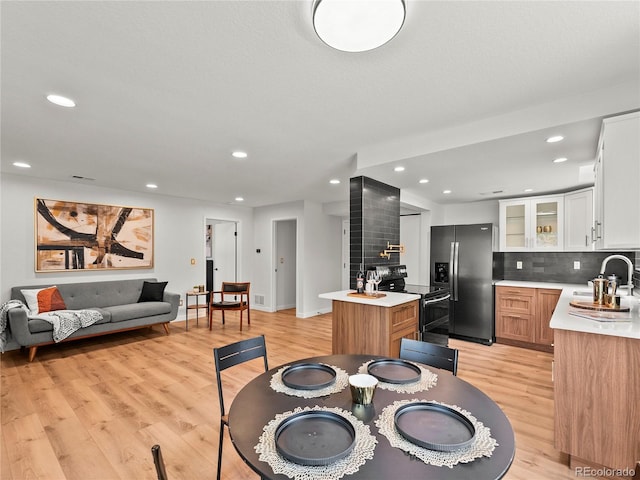 dining area with light wood-style floors, recessed lighting, wet bar, and baseboards