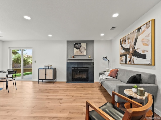 living area with light wood-style flooring, recessed lighting, a fireplace, and baseboards