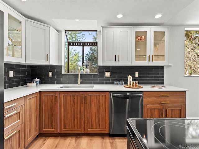kitchen with dishwasher, a sink, light countertops, decorative backsplash, and recessed lighting