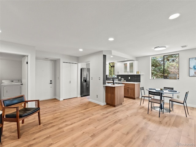 kitchen featuring washer / dryer, stainless steel fridge with ice dispenser, light countertops, recessed lighting, and decorative backsplash