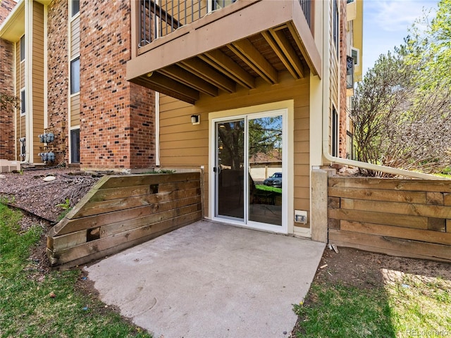 entrance to property featuring a patio, a balcony, and brick siding