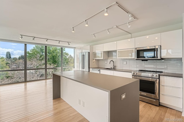 3100 E Cherry Creek S Drive 404, Denver, CO 80209 - kitchen featuring appliances with stainless steel finishes, a sink, white cabinetry, modern cabinets, and backsplash
