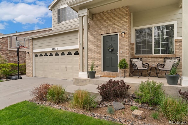 10475 E Abilene St, Commerce City, CO 80022 - doorway to property featuring brick siding, concrete driveway, an attached garage, and covered porch