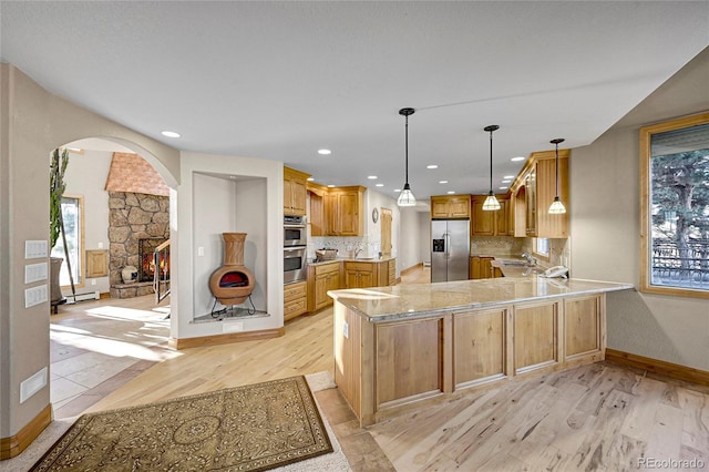 kitchen featuring backsplash, light wood-type flooring, kitchen peninsula, and appliances with stainless steel finishes