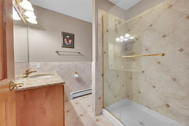 bathroom with vanity, tile walls, baseboard heating, and a shower with shower door