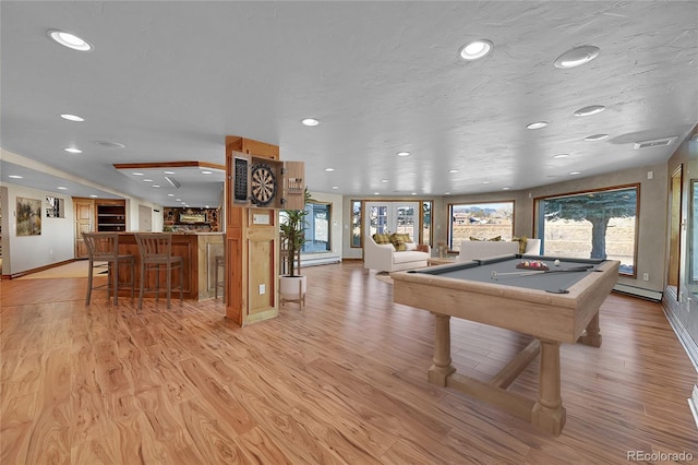 game room with indoor bar, pool table, a textured ceiling, and light wood-type flooring