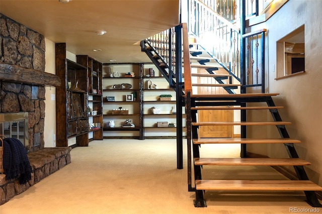 staircase with a stone fireplace and carpet floors