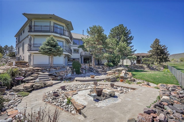 back of property featuring a balcony, fence, and stucco siding