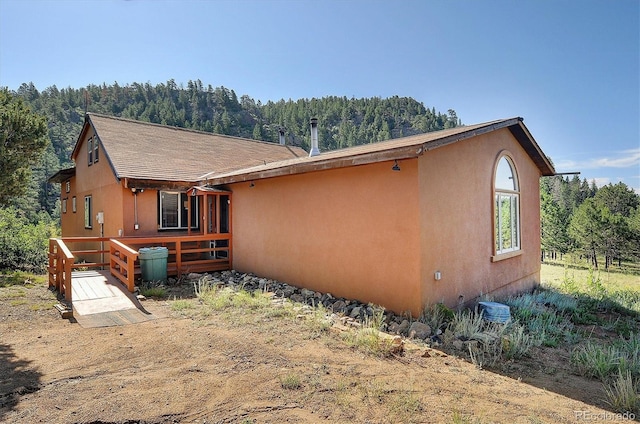 1111 Red Feather Rd, Cotopaxi, CO 81223 - view of front of house with a view of trees, stucco siding, and a wooden deck