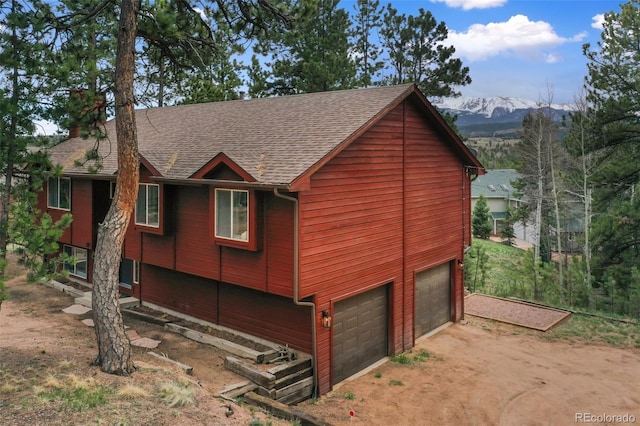 121 Aspen Dr, Woodland Park, CO 80863 - view of home's exterior with a garage, roof with shingles, a mountain view, and dirt driveway