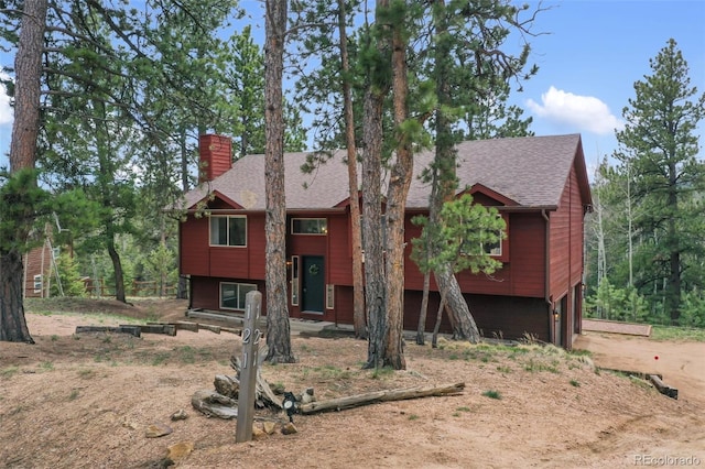 121 Aspen Dr, Woodland Park, CO 80863 - split foyer home featuring a chimney, dirt driveway, a garage, and a shingled roof