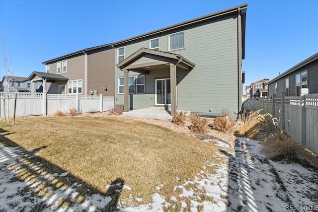 snow covered back of property featuring a patio area and a lawn